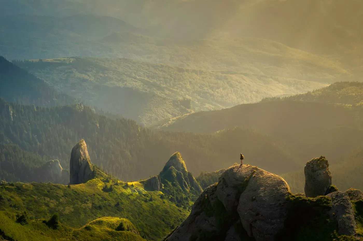 Traveler looking out across a mountain valley at sunrise